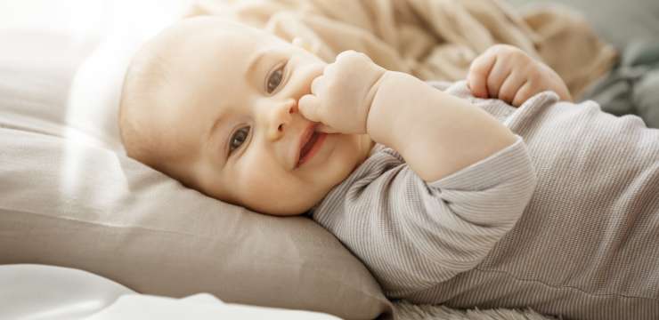 sweet smiling newborn daughter lying on cozy bed